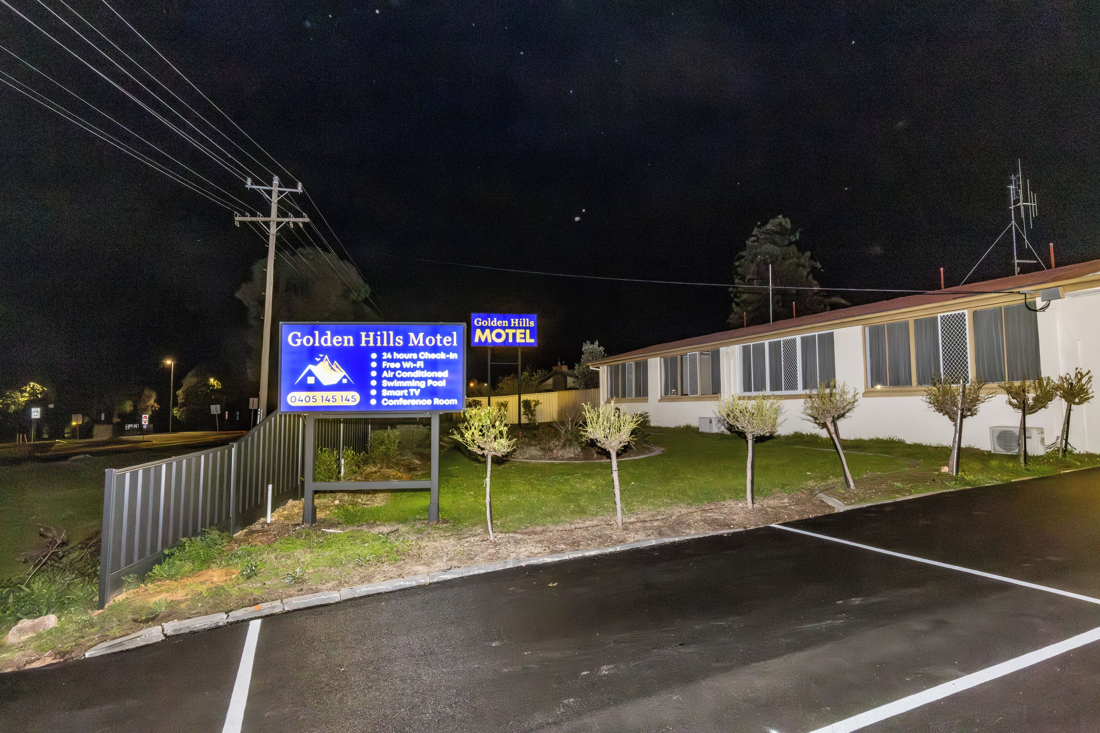 Un letrero de motel que enumera sus servicios, entre ellos, acceso las 24 horas, Wi-Fi gratuito, aire acondicionado, piscina, televisor inteligente y una sala de conferencias.