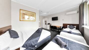 Une chambre d’hôtel avec deux lits simples, un bureau, une chaise, un téléviseur à écran plat et un appareil de climatisation.