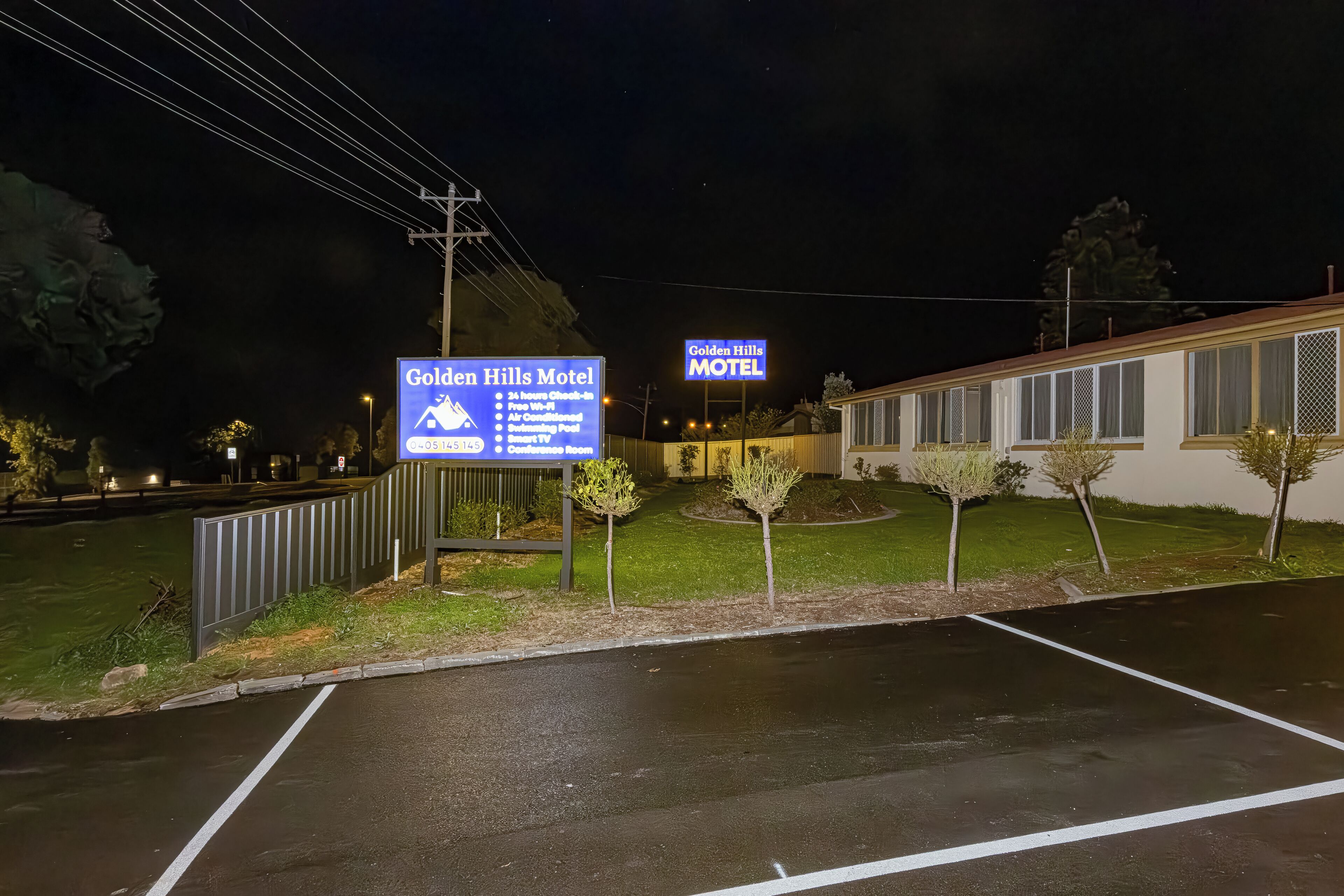Motelbordes met opsomming van voorzieningen, waaronder 24-uurs receptie, gratis Wi-Fi, airconditioning, een zwembad en een smart-tv.