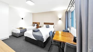 A hotel room with two beds, a wooden table, and a chair.