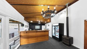 Un área de recepción con mostrador de madera, refrigerador negro y techo revestido de madera.