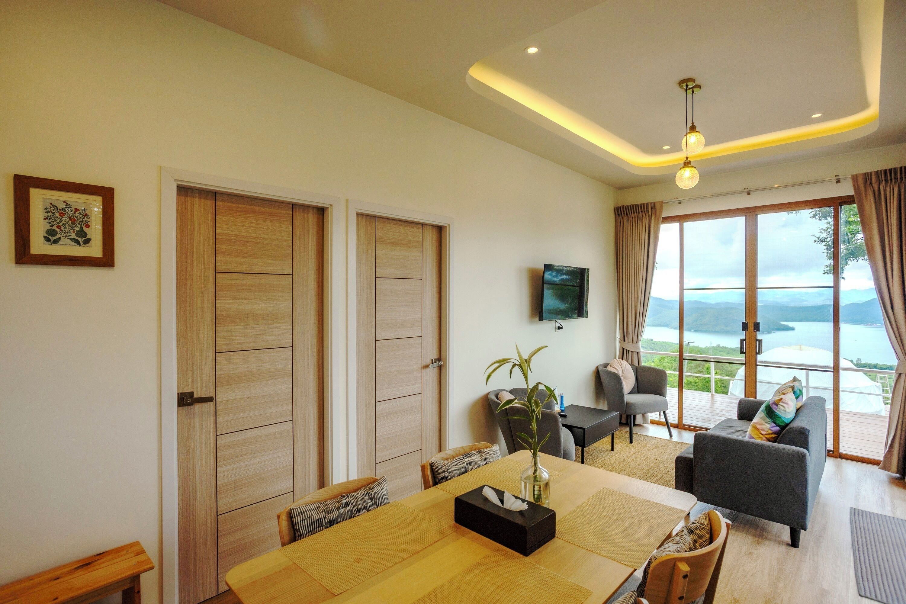 A modern living room with a dining area, large windows, and a view of the outdoors.