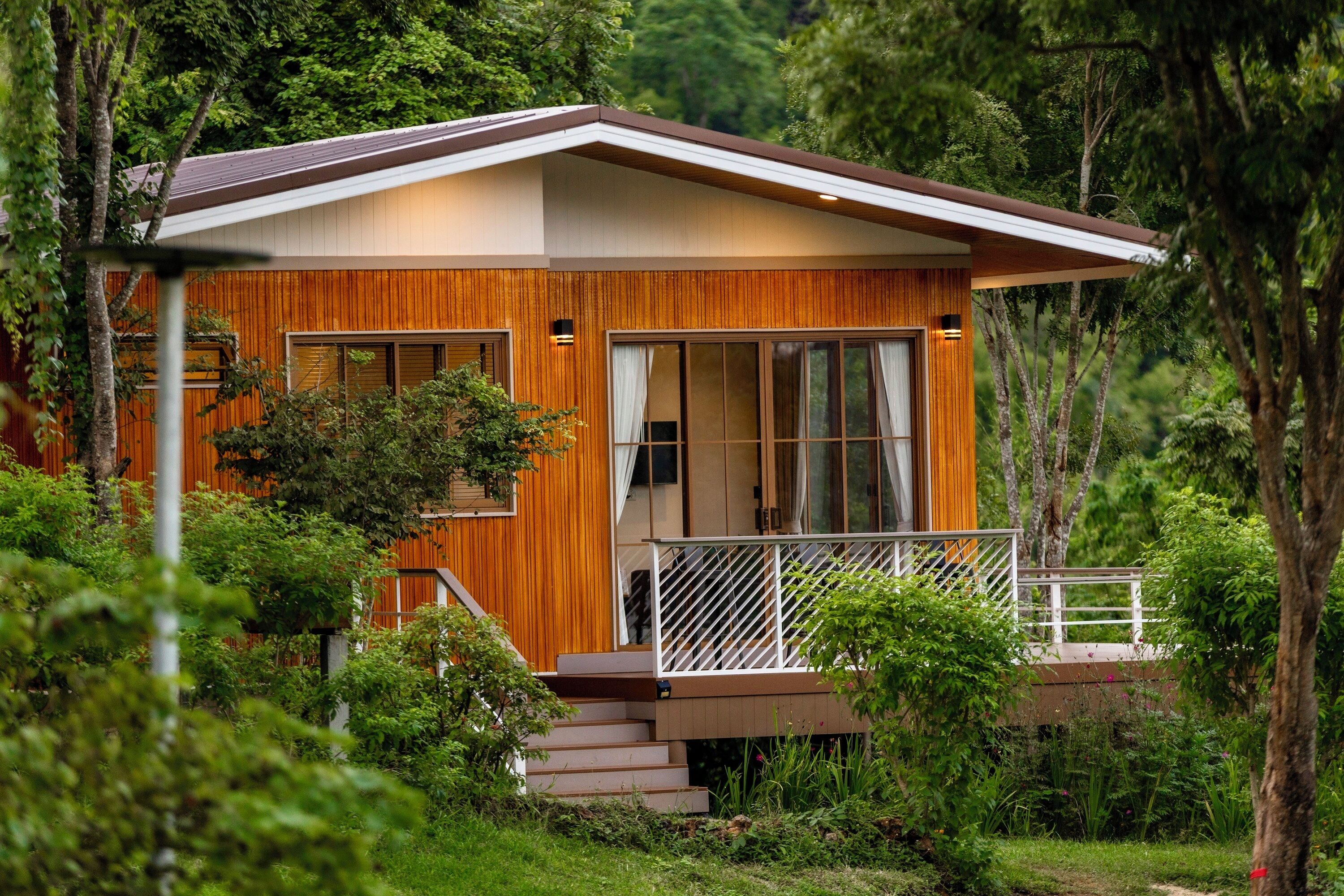 A modern house with a wooden exterior, large windows, and a balcony.