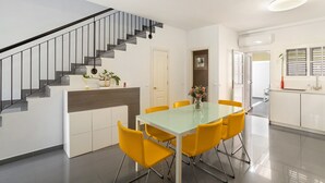 Una cocina moderna con armarios blancos, una mesa de comedor de cristal y sillas amarillas.