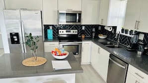 A modern kitchen with white cabinets, a black countertop, a built-in oven, and a stainless steel dishwasher.