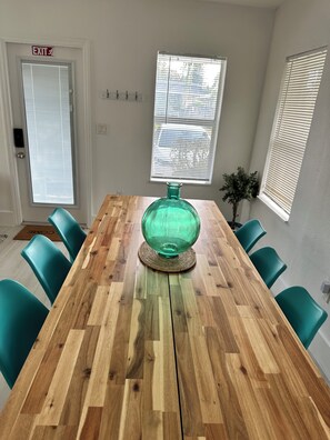A conference room with a wooden table, teal chairs, and a green glass vase centerpiece.