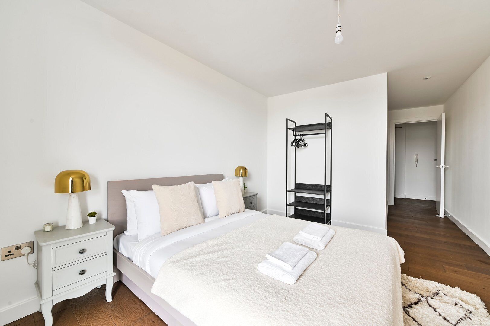 A neatly arranged bedroom with a bed, bedside tables, a lamp, and a wardrobe.