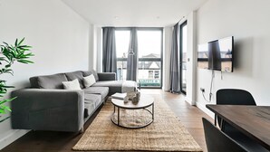 Un salon moderne avec un canapé gris, une table basse et un téléviseur fixé au mur.