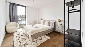 Une chambre moderne comprenant un lit, des tables de chevet, une armoire suspendue, une chaise et une grande fenêtre.