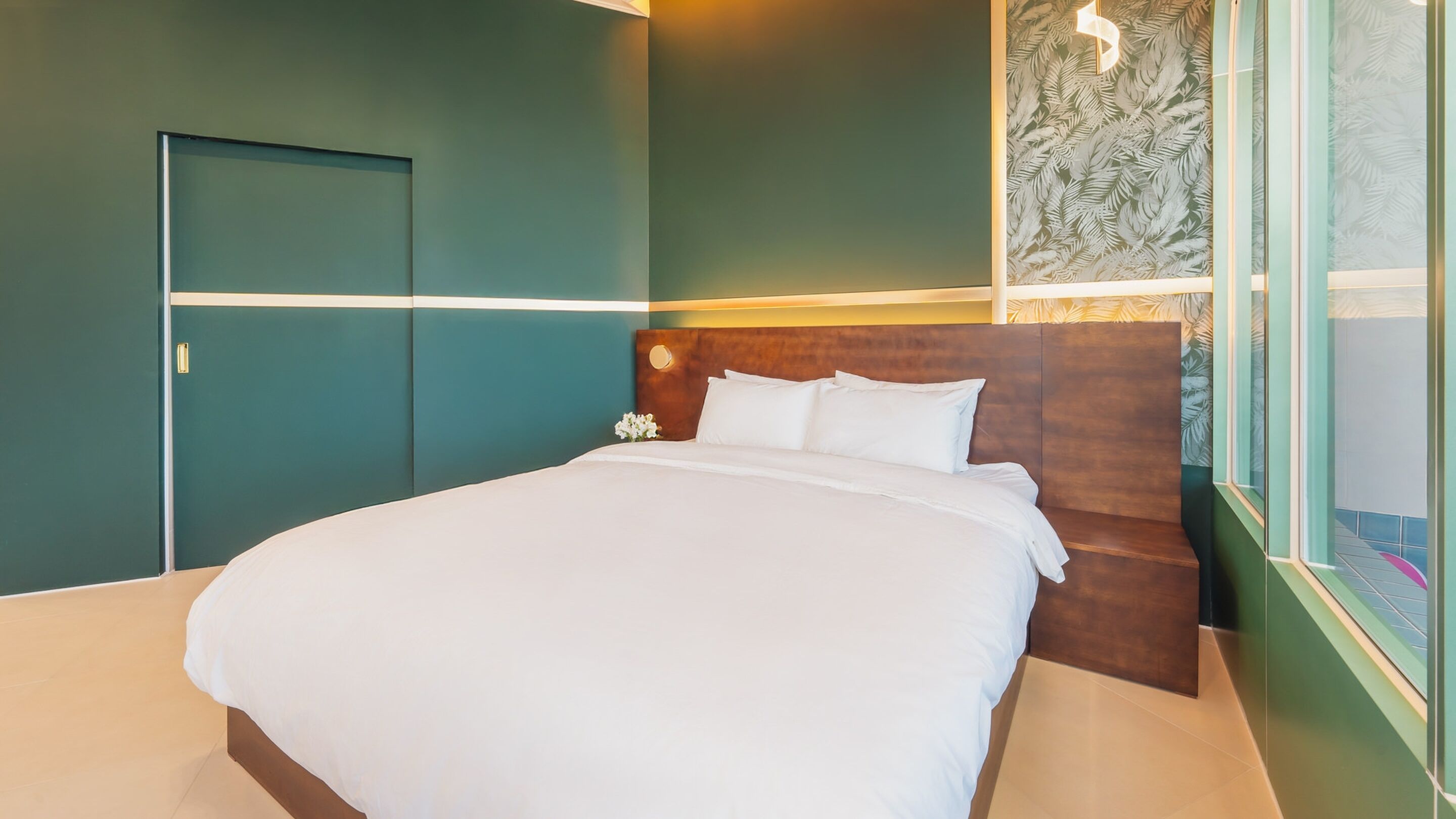 Une chambre d’hôtel moderne avec un grand lit, une tête de lit en bois et une vue sur la ville par la fenêtre.
