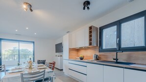A modern kitchen with white cabinets, a wooden countertop, and a large window. - Collioure le haut by Interhome (Collioure)