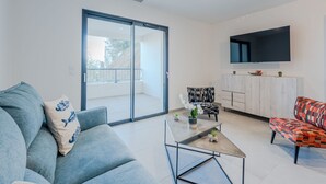 A modern living room with a sofa, armchair, coffee table, and a TV mounted on the wall. - Collioure le haut by Interhome (Collioure)