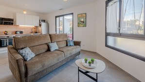 A modern living room with a sofa, a small table with plants, and a kitchen in the background. - Collioure le haut by Interhome (Collioure)