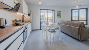 A modern kitchen with a dining area, a sofa, and a view through the glass door. - Collioure le haut by Interhome (Collioure)