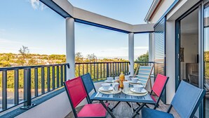 A covered outdoor dining area with a table set for four, surrounded by chairs, and a view of a residential area in the background. - Collioure le haut by Interhome (Collioure)