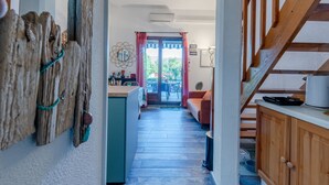 Un pasillo con una escalera de madera, una zona de cocina con mesa de comedor y vistas al exterior.