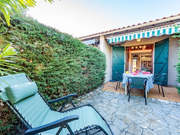 A patio with a table and chairs, a green door, and a stone pathway. - Les Brigantines 1 et 2 by Interhome (Saint Cyprien)