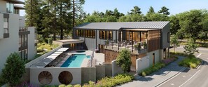 Un bâtiment moderne doté d’une piscine sur le toit, d’un espace extérieur aménagé et d’une grande baie vitrée.