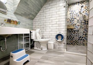 Bathroom features a toilet, sink, and shower area with a patterned tile design.