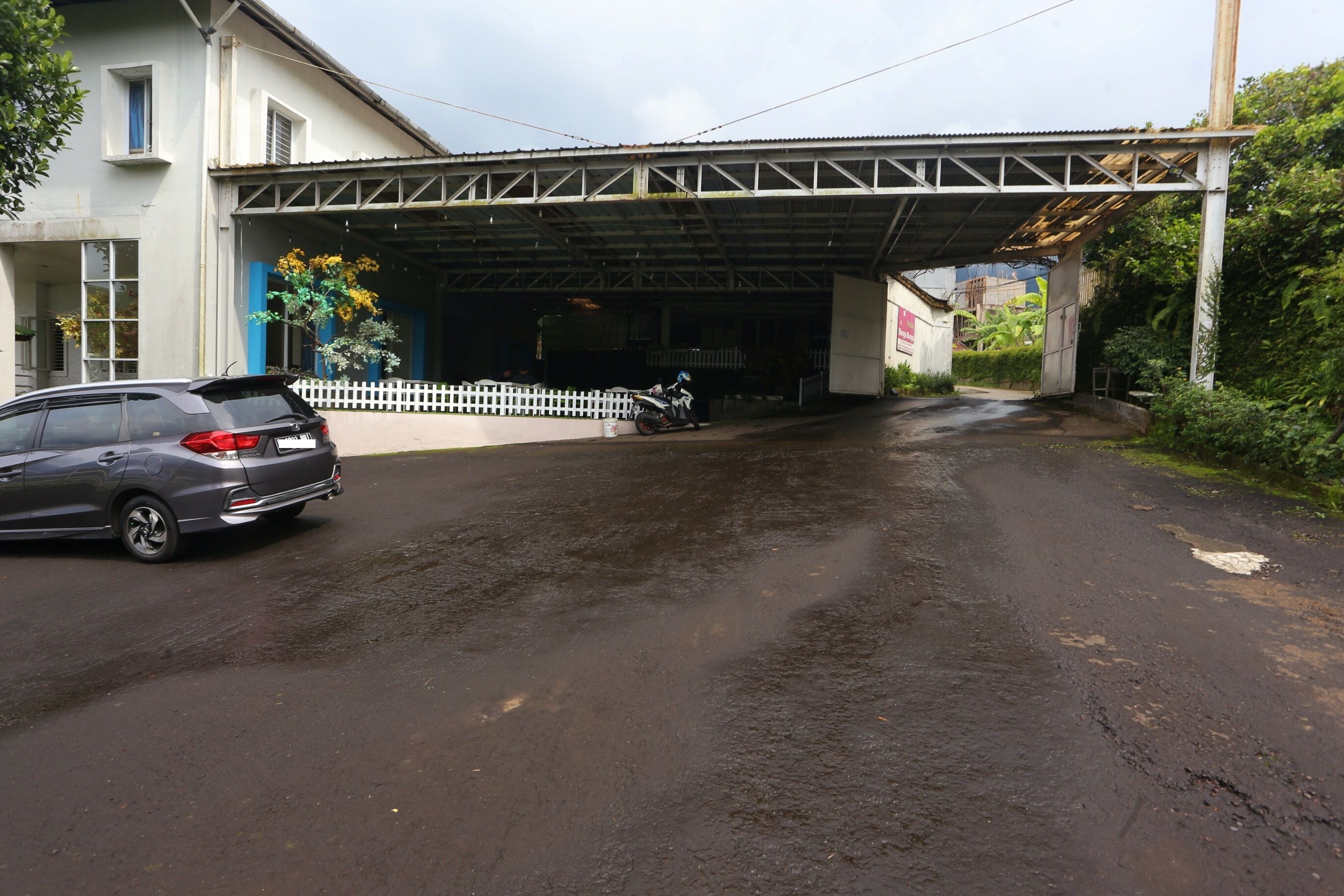 A building with a covered entrance, a parked car, and a motorcycle.