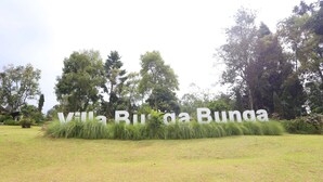 Schild für Villa Burga Bunga mit einer grasbewachsenen Vordergrund und Bäumen im Hintergrund.