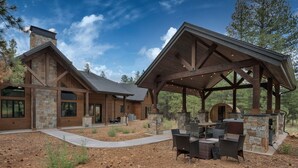Una casa moderna con fachada de piedra, ventanas amplias y un porche cubierto con mobiliario exterior.