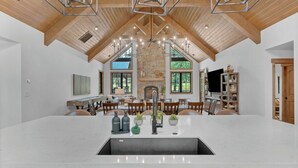 Una cocina amplia con una isla grande, chimenea de piedra y vigas de madera.