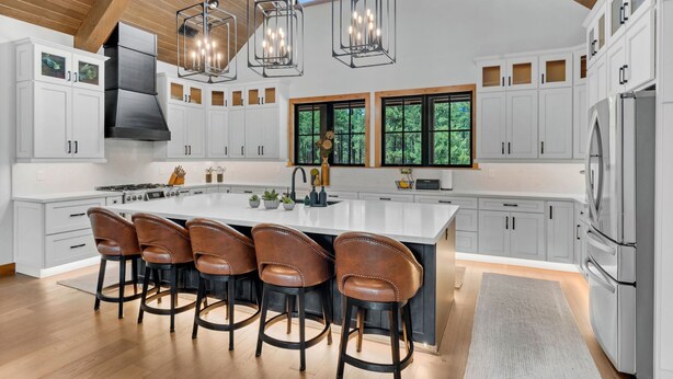 Una cocina moderna con una isla grande, taburetes de bar e iluminación colgante.