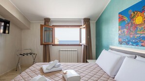 A hotel room with a bed, a window with curtains, a radiator, a towel rack, and a painting on the wall. - Pirandello by Interhome (Balestrate)