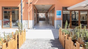 A corridor with wooden planters, glass doors, and a staircase leading to an upper floor.