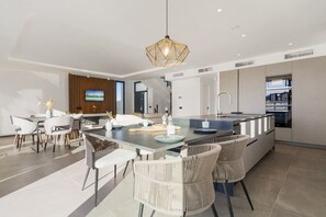 A modern kitchen with a central island, built-in appliances, and a dining area with chairs and a table. - Mijas Villa w/ Private Pool & Panoramic Mountain (La Cala de Mijas)