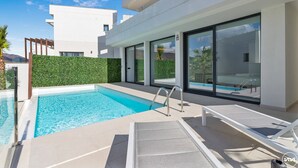 A modern pool area with clear blue water, a glass-enclosed pool, and lounge chairs. - Villa Kolibri | Mountain view - pool - garden (La Cala de Mijas)