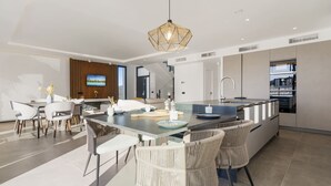 A modern kitchen with a central island, white chairs, and a hanging light fixture. - Villa Kolibri | Mountain view - pool - garden (La Cala de Mijas)