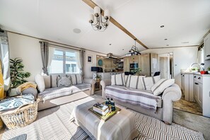 Een ruime woonkamer met een zithoek, een salontafel, en een eethoek met een keuken op de achtergrond.