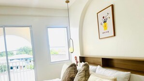 Ein Schlafzimmer mit einem Bett, zwei Kissen, einer Nachttischlampe und einem gerahmten Bild an der Wand.
