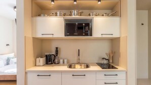 Una kitchenette compacta con microondas, lavamanos y armarios de almacenamiento.
