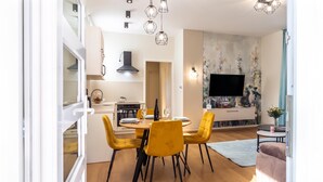 A modern kitchen with a dining area, a flat-screen TV, and a sofa.
