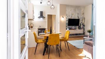 A modern kitchen with a dining area, a flat-screen TV, and a sofa.