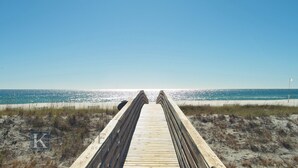 Una passerella di legno che conduce a una spiaggia sotto un cielo sereno.