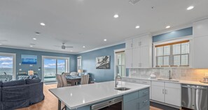 A modern kitchen with a central island, stainless steel appliances, and a dining area with a view.