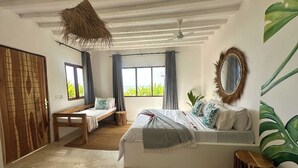 A bedroom with a bed, a bench, a mirror, and a view of the outdoors. - Garden Beach Bungalows (Jambiani)