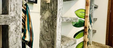 A room with a marble floor, a wooden shelf with a green leaf design, and a coat rack with a hanging garment.