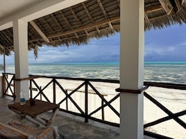 A beachside structure with a thatched roof, wooden railings, and a view of the ocean.