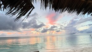 A beach view with a thatched roof structure. - Garden Beach Bungalows (Jambiani)