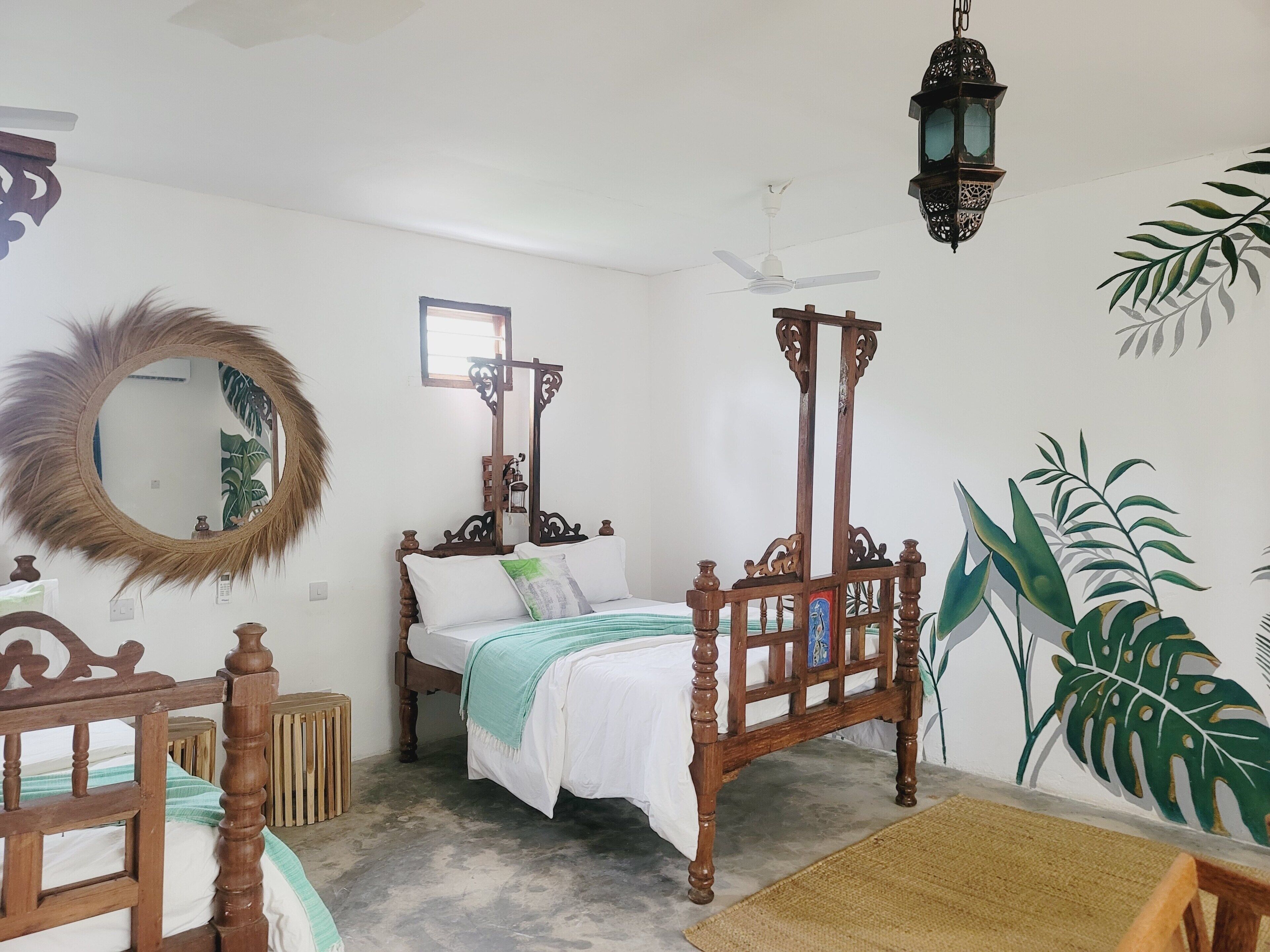 A bedroom with a wooden bed, a round mirror, a ceiling fan, and a wall-mounted lantern.