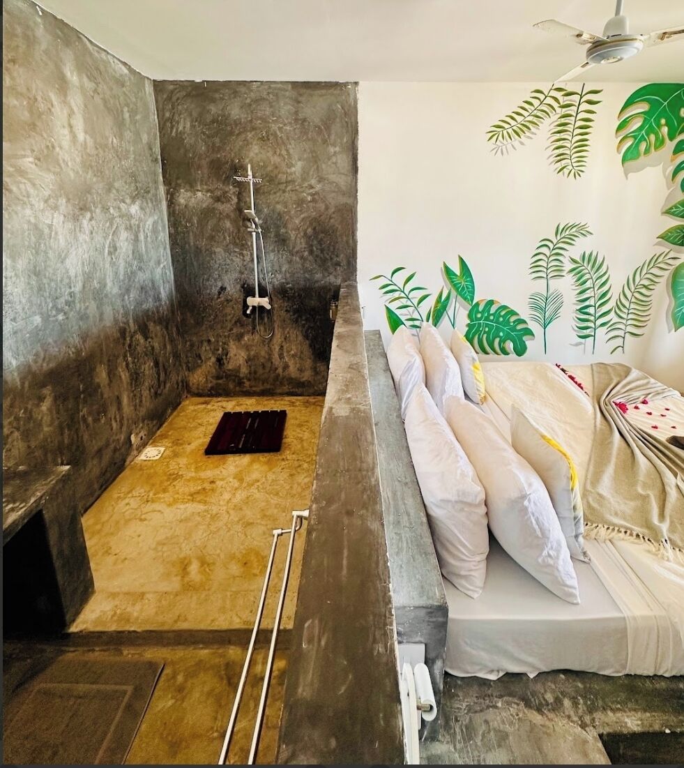 Une chambre avec une douche, un lit avec des oreillers et un mur orné de motifs de feuilles.