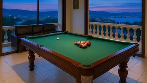 A pool table with a view of a mountainous landscape through large windows. - Aksarai otel Patong  (Patong)