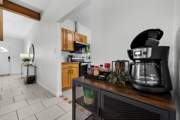A modern kitchen with wooden cabinets, a coffee maker, and a coffee bar.