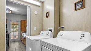 Ein Waschraum mit zwei weißen Amana Waschmaschinen, Holzausbau und einem kleinen Fenster.