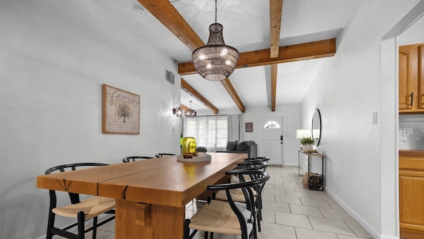 Ein Essbereich mit Holztisch und -stühlen, einer Chandelierleuchtre und einem gerahmten Bild an der Wand.